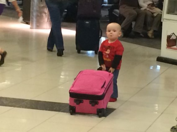 Toddler pulling pink suitcase at airport