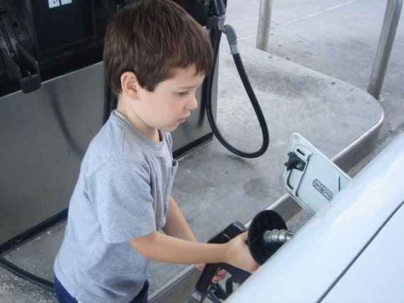 child learning how to put gas in a car
