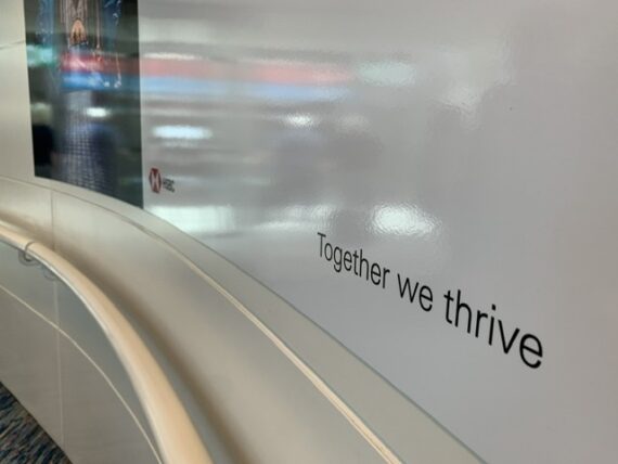 together we thrive sign on airport wall