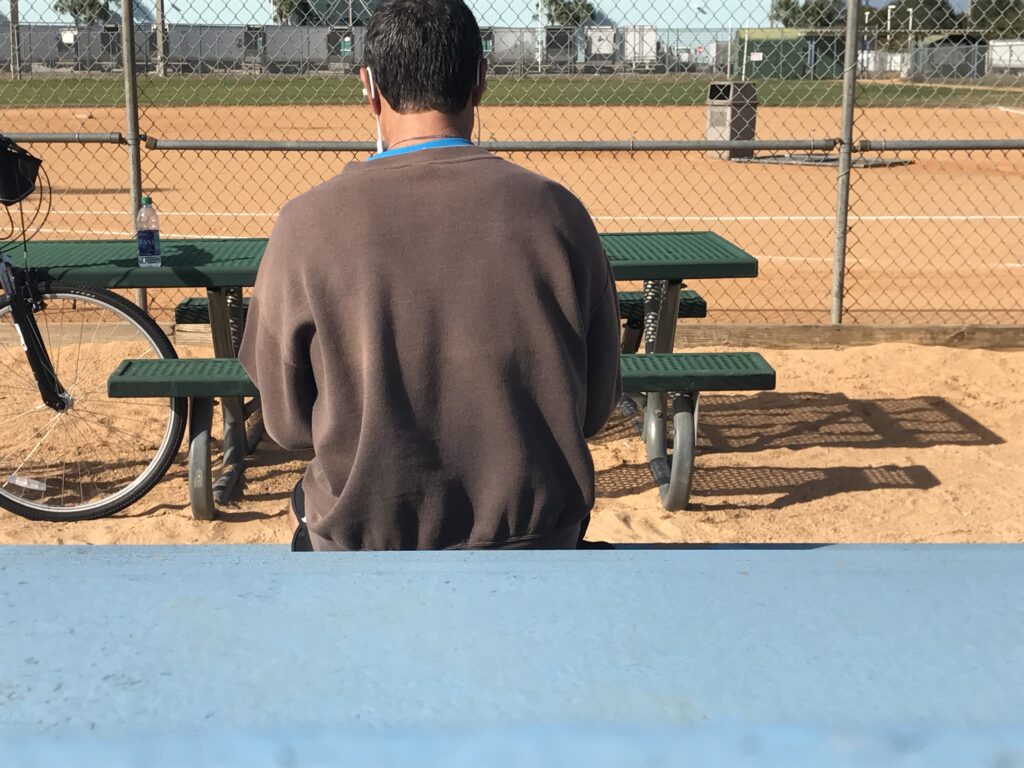 man with back turned at a softball field