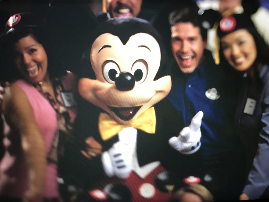 People surrounding Mickey Mouse for a photo