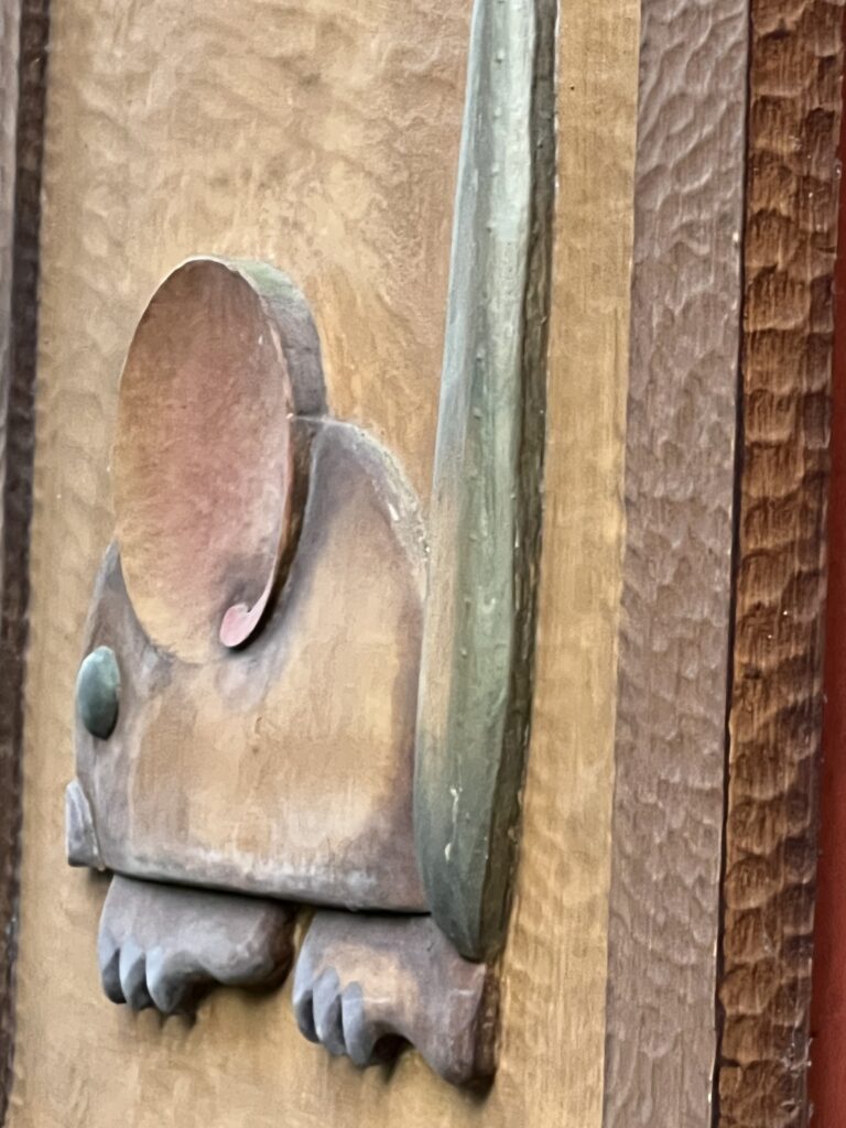 Wood carving of mouse on a wall