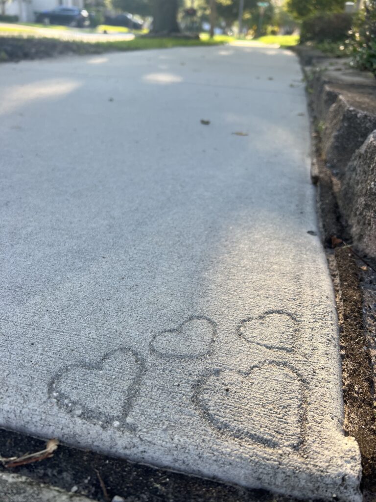 Four heart shapes etched in sidewalk