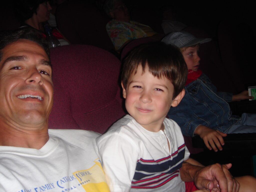 Father and son sitting in a theater
