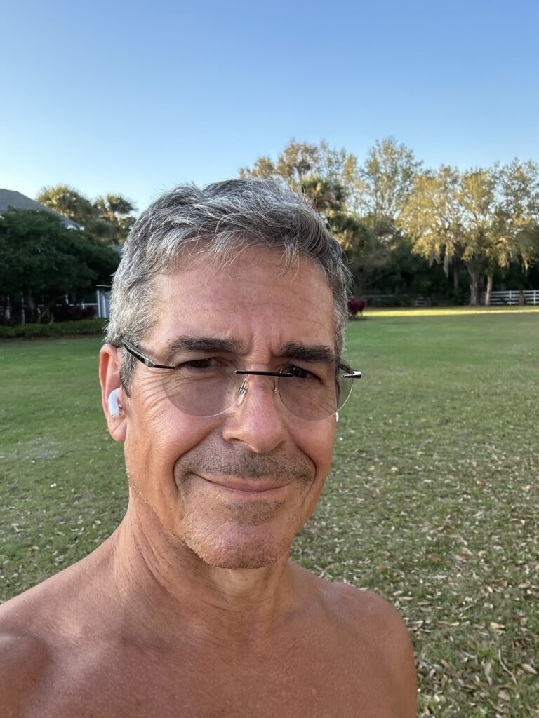 Shirtless man smiling in a yard