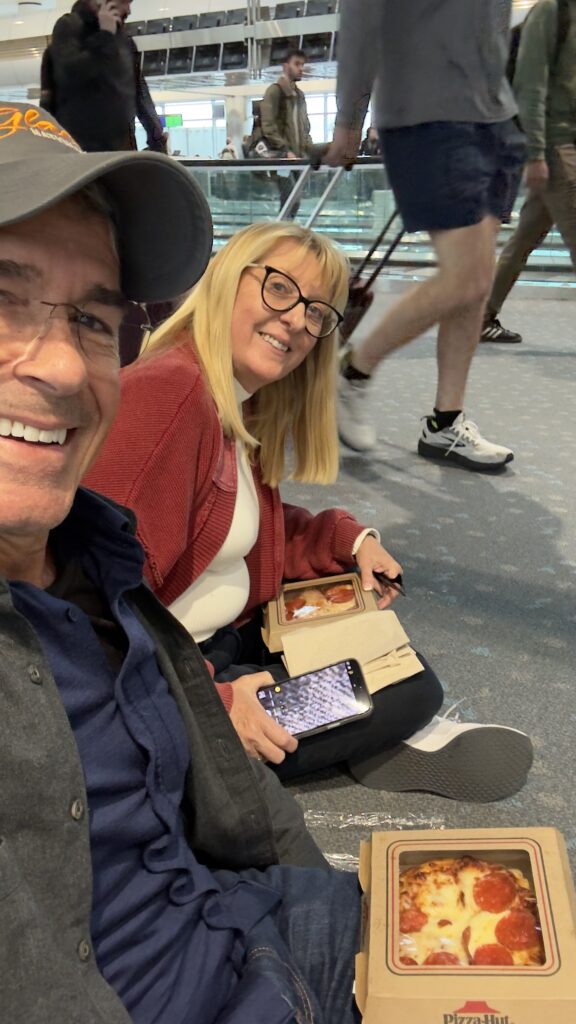 Two people sitting on airport floor