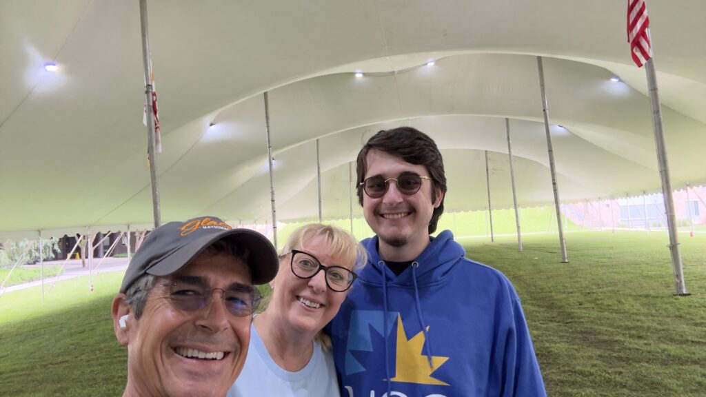 three adults under a big tent