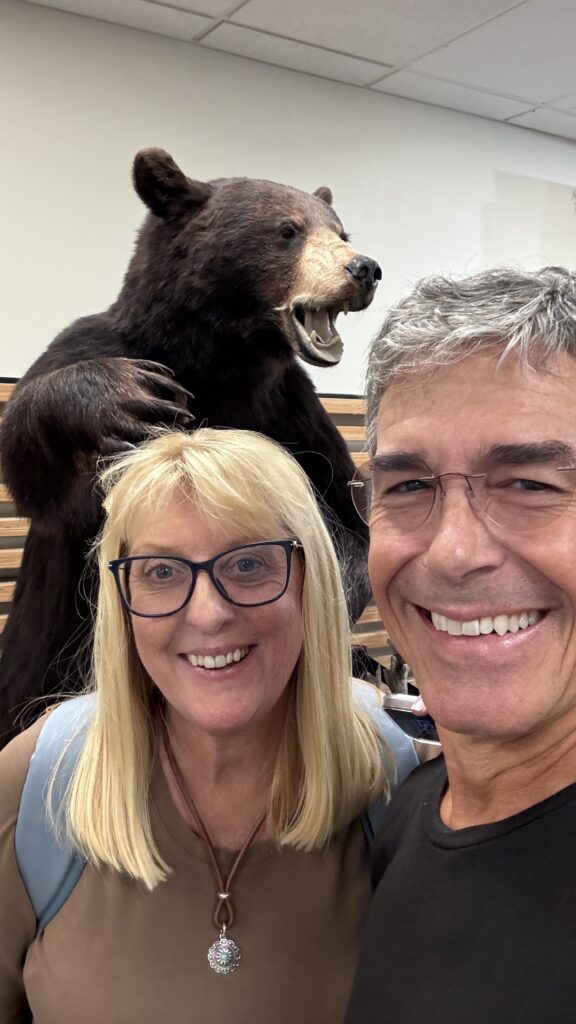 Two people posing in front of a stuffed grizzly bear