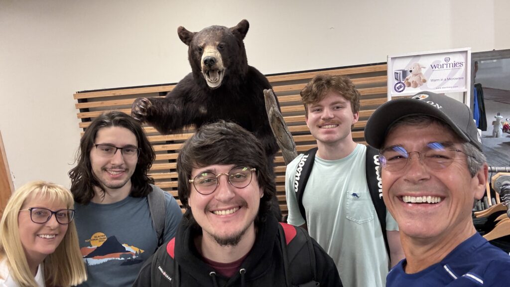 five people posing in front of a stuffed Grizzly Bear