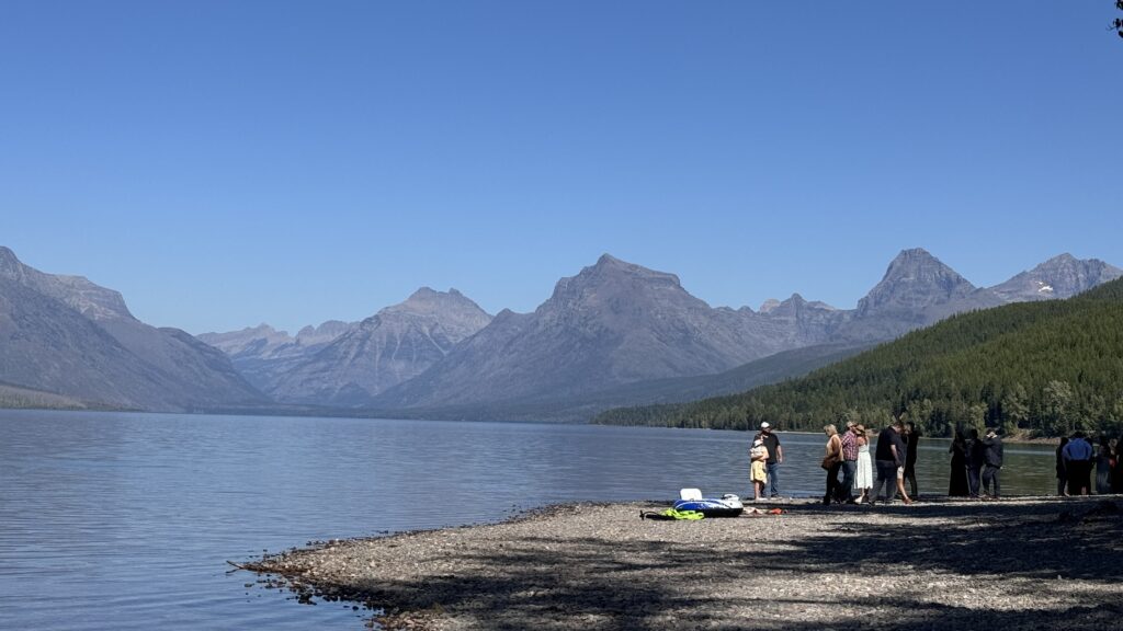people standing next to a mountain lake